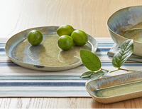 large plate with glossy finish, limes and a lime leave on a table with a striped runner