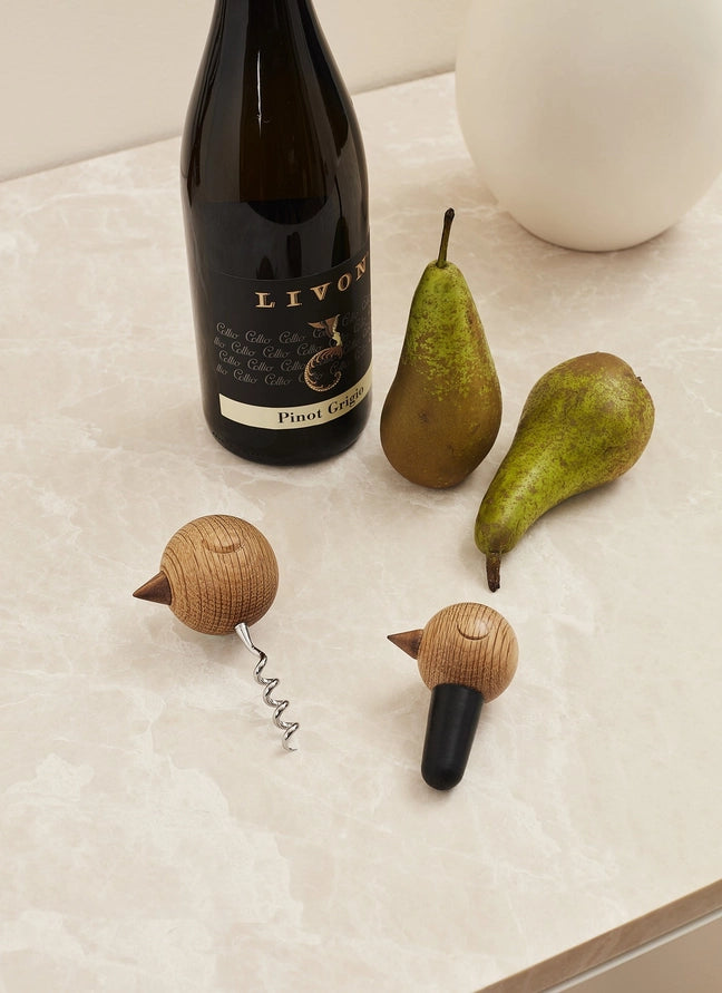 Nordic style corkscrew and wine stopper on a marble table with a bottle of wine and two pears