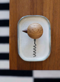 metal corkscrew with a Nordic style wooden head of bird on white plate