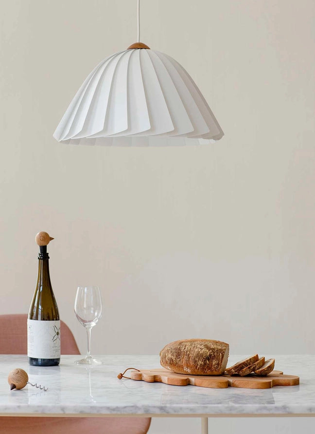 metal corkscrew with a Nordic style wooden head of bird on a marble table with bottle of wine and sliced bread