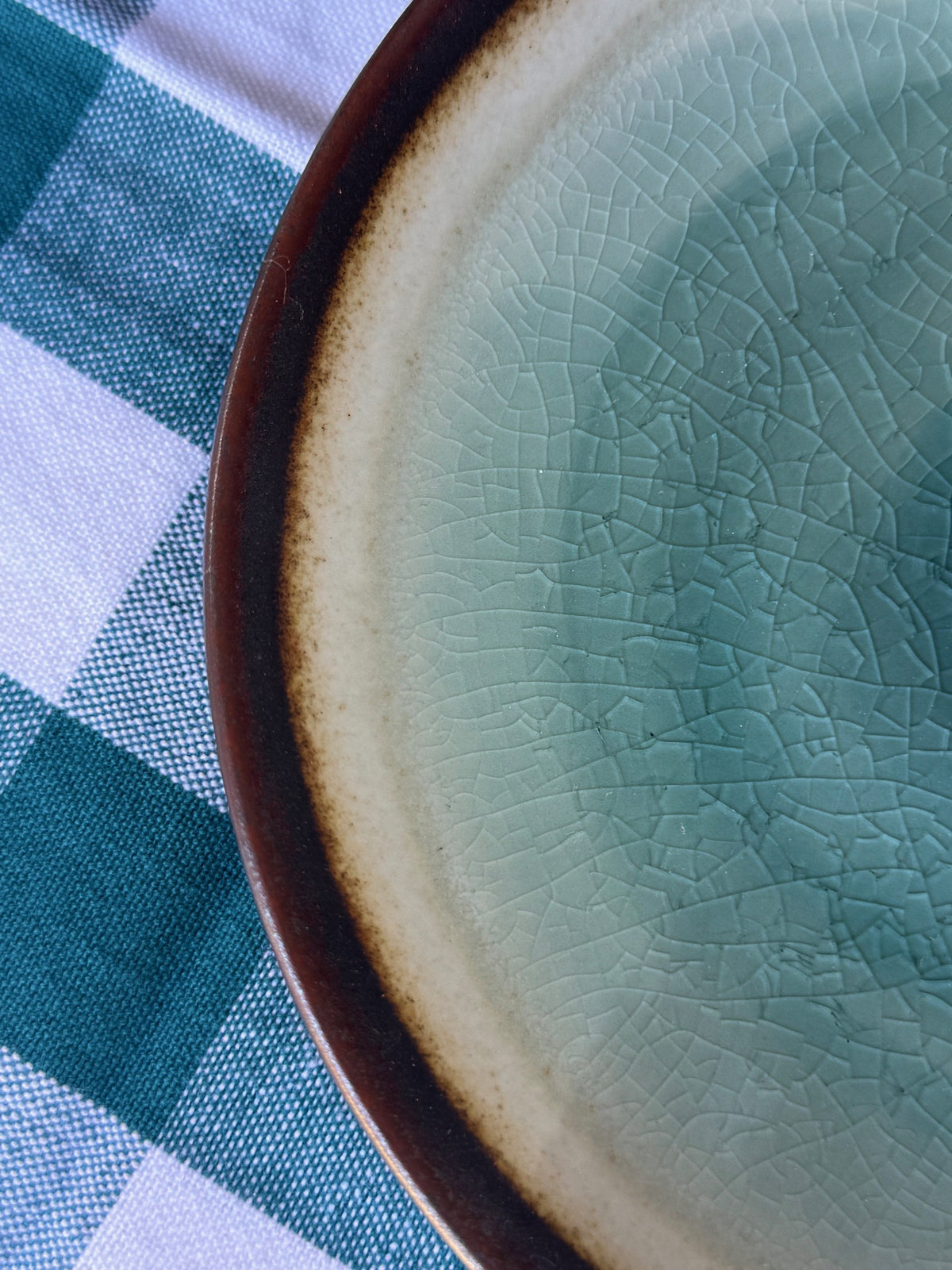 Close-up of a ceramic plate with a textured surface on a checkered cloth background