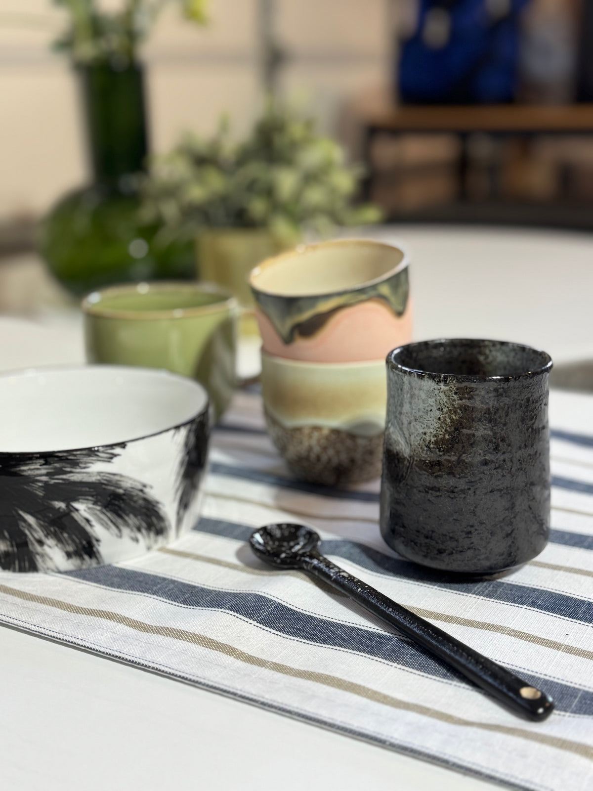 Ceramic bowls and a black spoon on a striped tablecloth with a blurred background