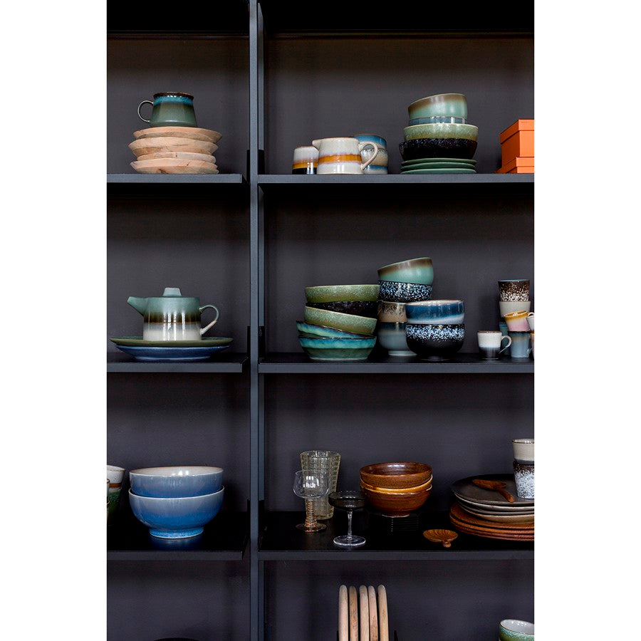 Shelves with various ceramic dishes and glasses against a dark background