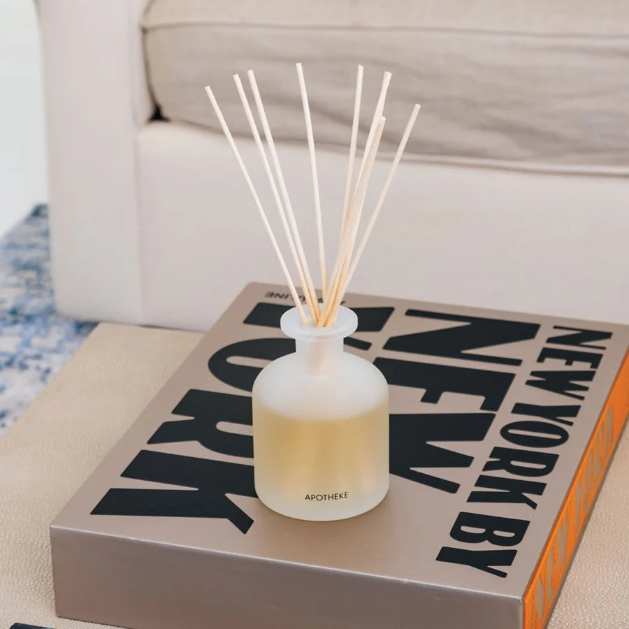 glass vessel with reed diffusers lavender scent on coffee table book