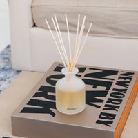 glass vessel with reed diffusers lavender scent on coffee table book