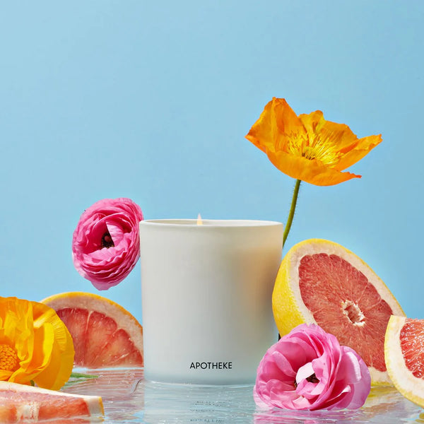 white glass vessel with flowers and grapefruit and blue backdrop