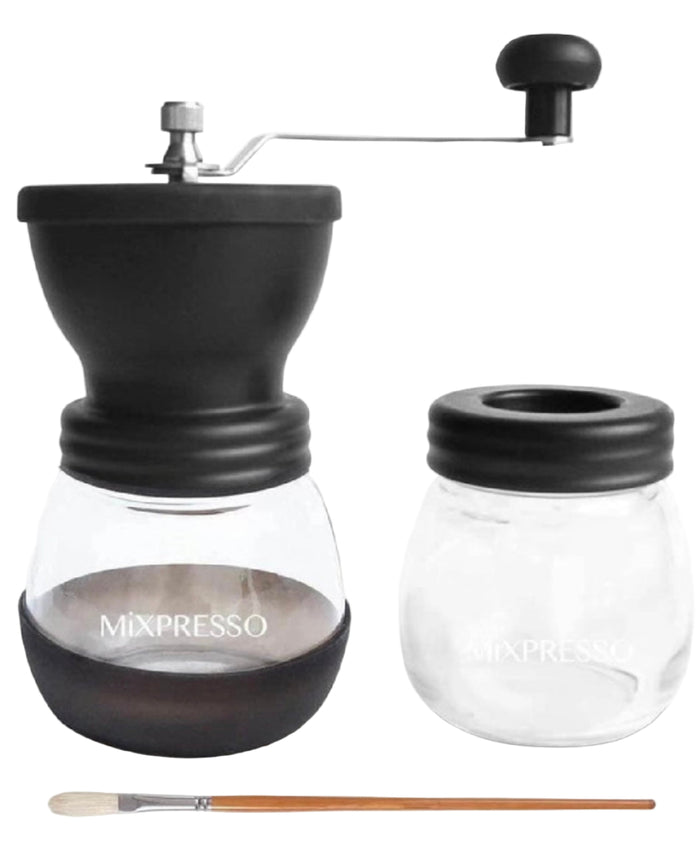 Black manual coffee grinder with clear container and brush on a white background