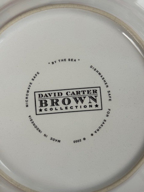 The bottom of a white ceramic plate or dish with printed black text reading 'DAVID CARTER BROWN COLLECTION' and surrounding safety text, photographed close up.
