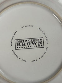 The bottom of a white ceramic plate or dish with printed black text reading 'DAVID CARTER BROWN COLLECTION' and surrounding safety text, photographed close up.