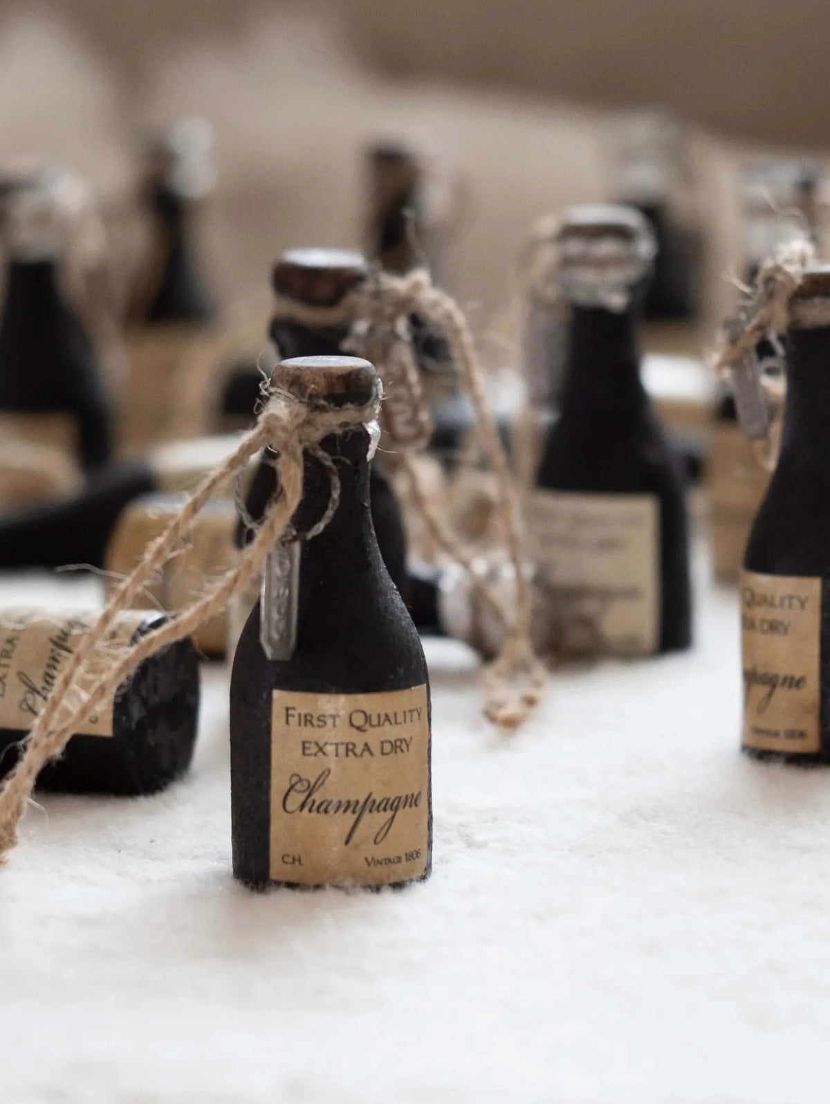Decorative miniature champagne bottles with labels on a white surface