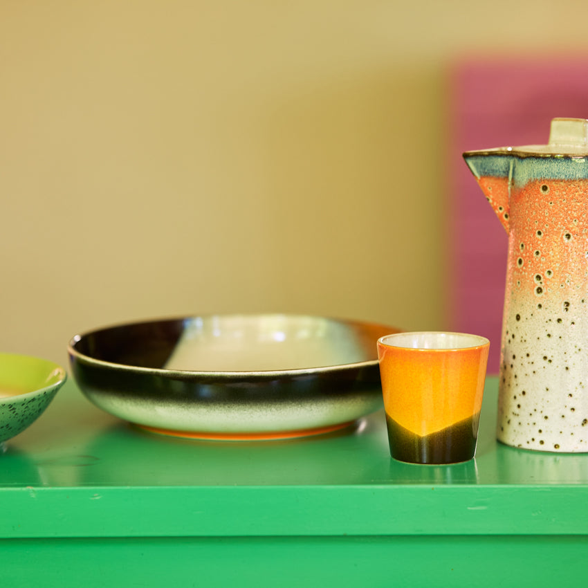 Set of ceramic dishes with colorful glazes on a green surface