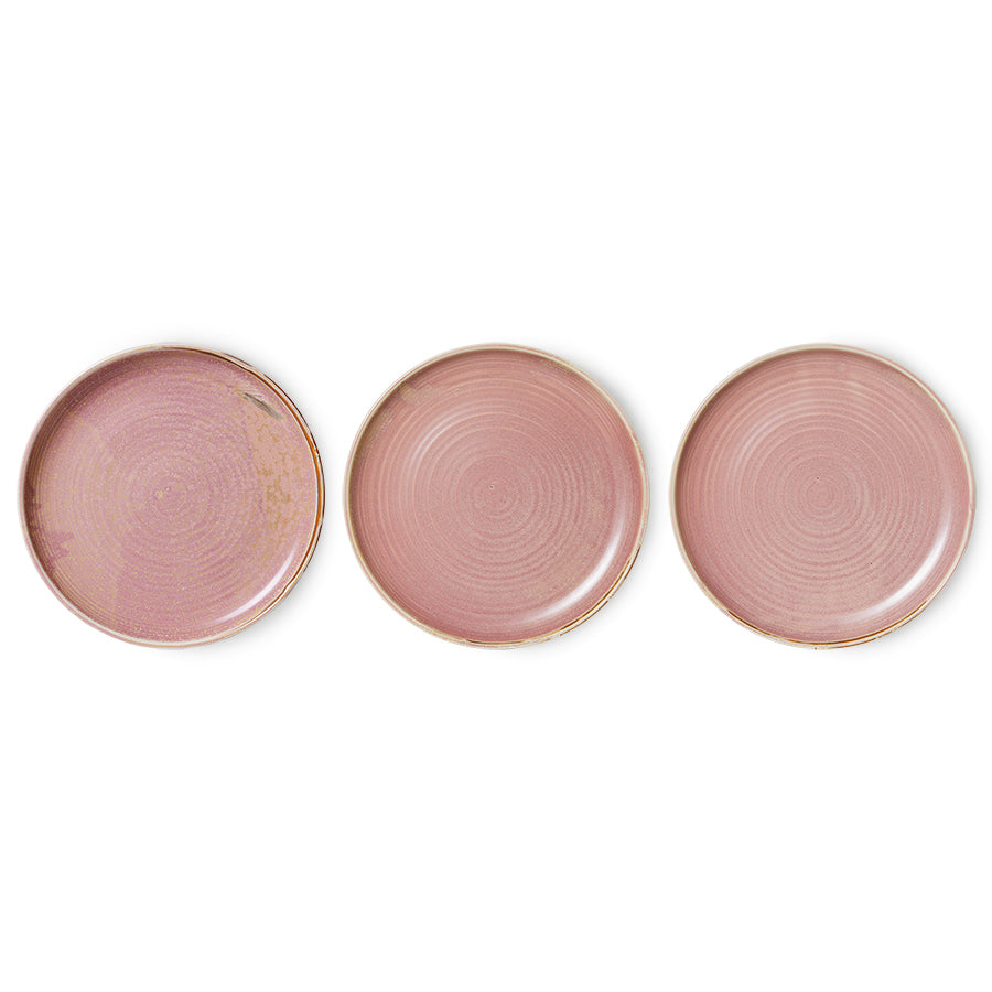 Three pink ceramic plates with gold rims on a white background