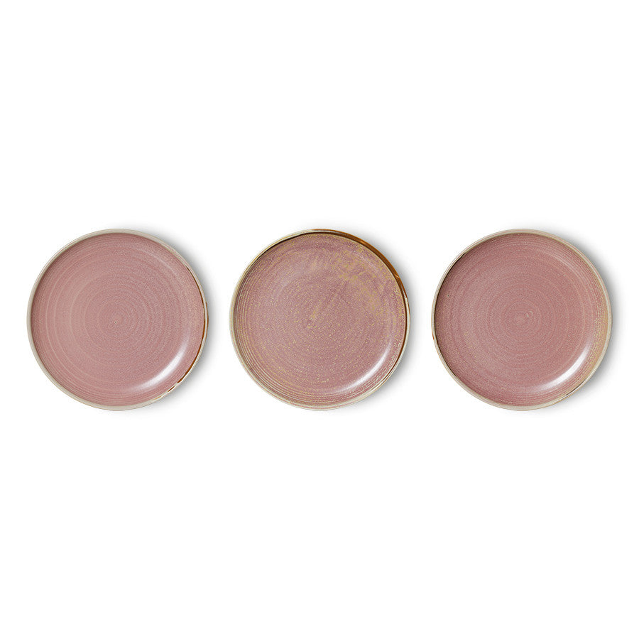 Three pink ceramic plates with gold rims on a white background