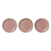 Three pink ceramic plates with gold rims on a white background