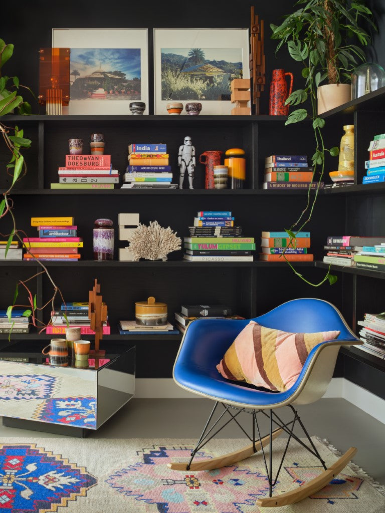black open shelving with books and home decor and blue chair with pillow