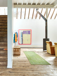 living room with green runner rug, yellow chairs and an pink framed abstract art work on white wall