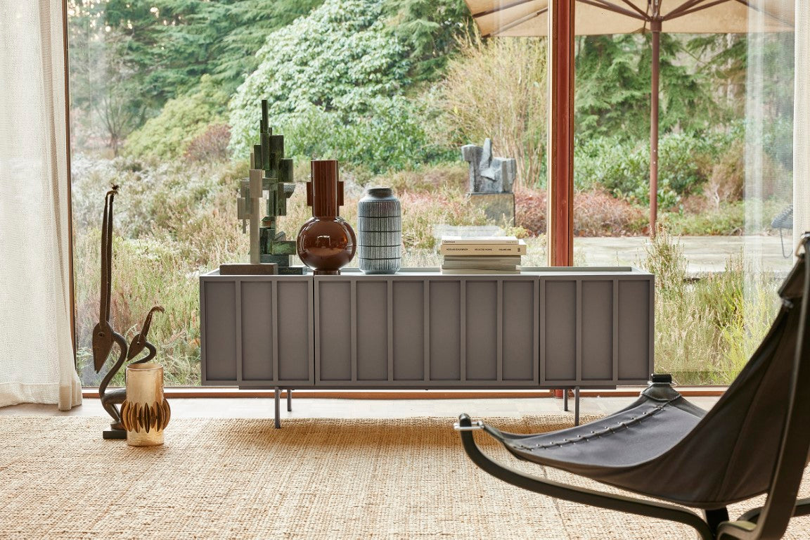 concrete grey tv stand low sideboard in front of window with sculptures and vases