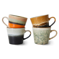 Set of four ceramic mugs with different color patterns on a white background