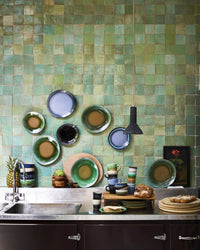Kitchen with green tiled wall and various ceramic dishes