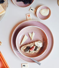 table filled with food and board games and rustic pink chef ceramics