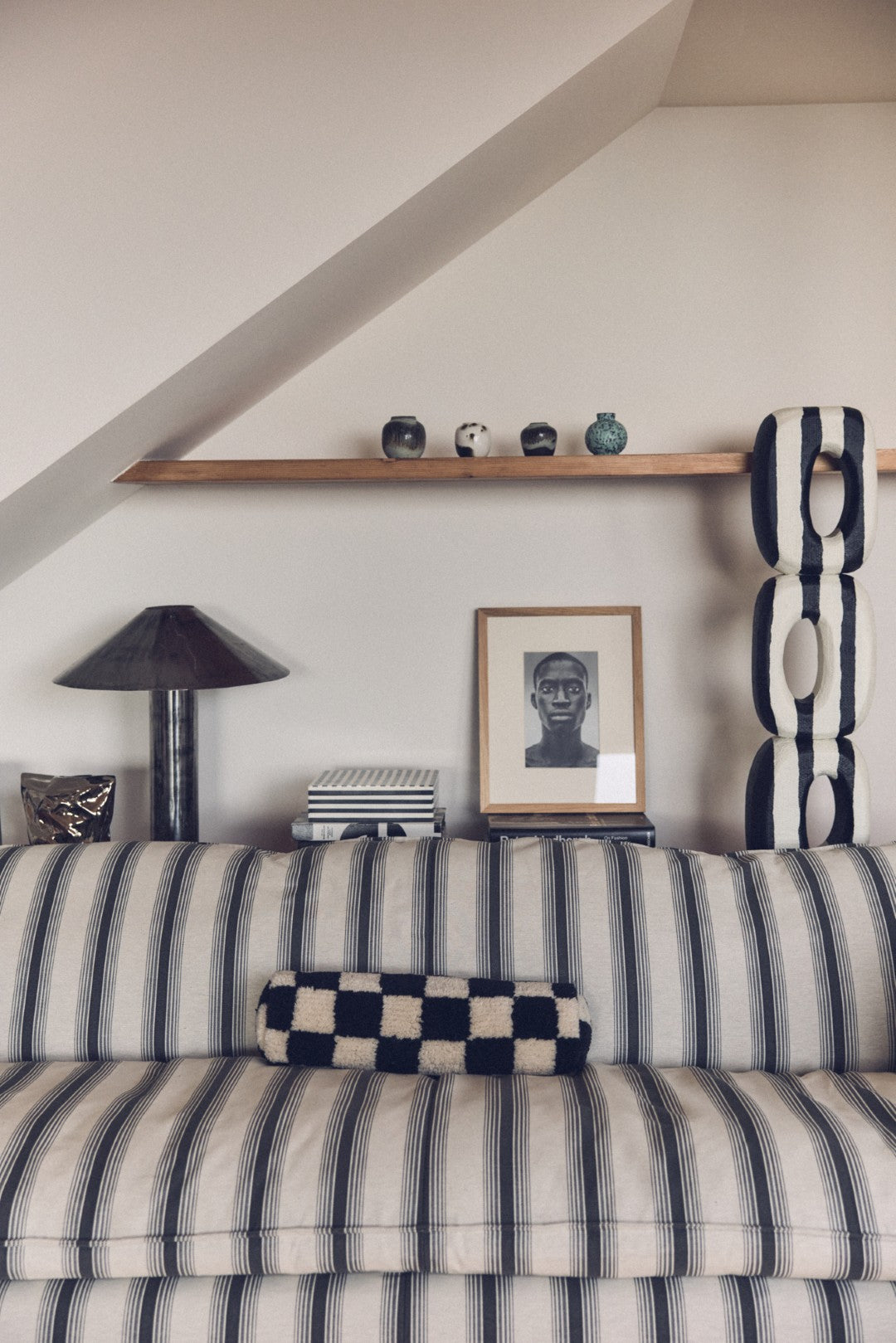 Living room with striped sofa, shelf, and decorative items.