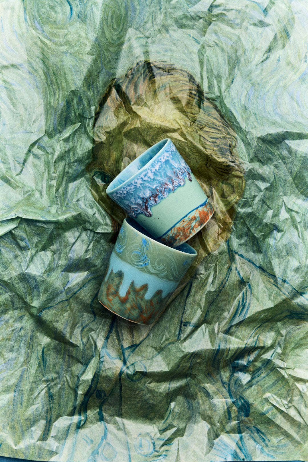 Two ceramic cups with decorative patterns on a crumpled green paper background
