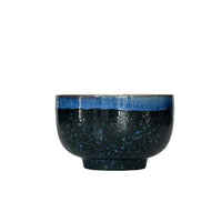 Black ceramic bowl with blue interior on a white background