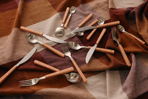 Wooden-handled cutlery set on a patterned fabric background