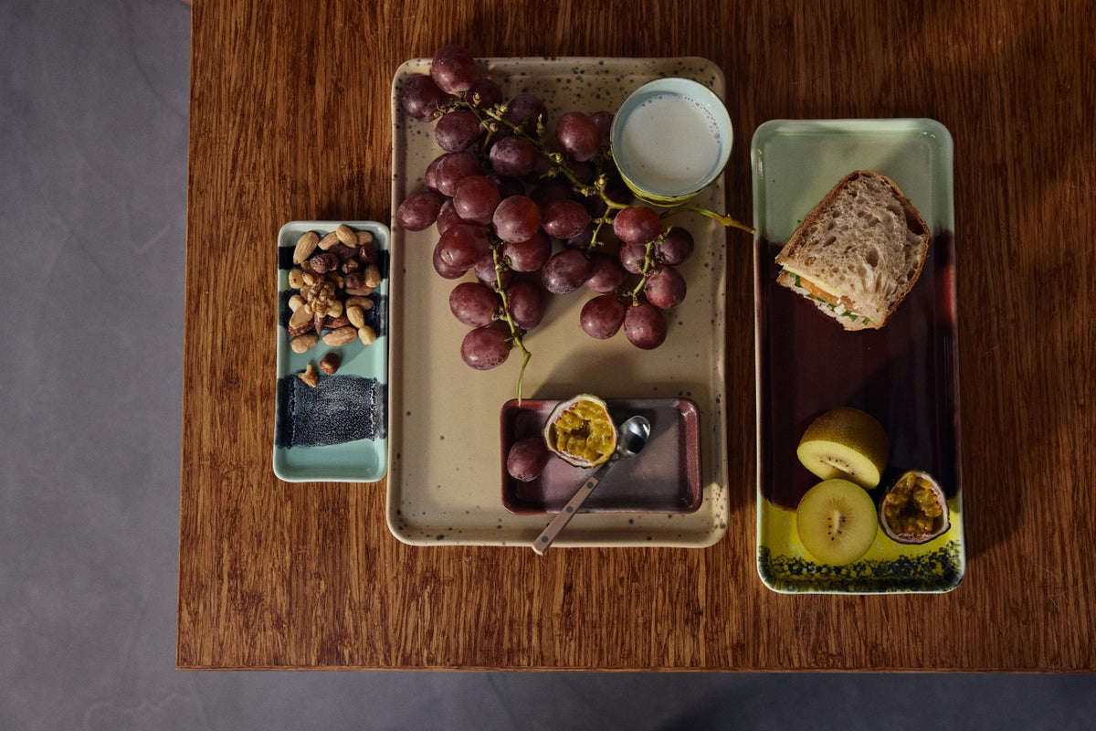 Platter with grapes, bread, and other items on a wooden table