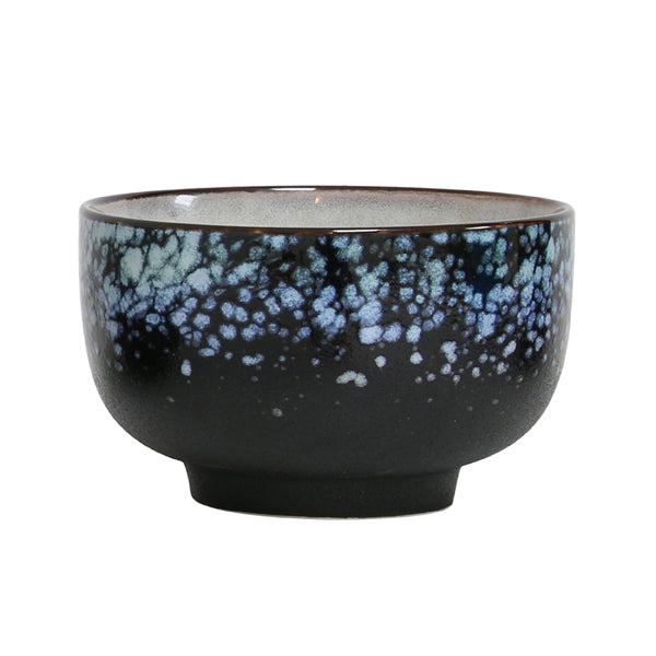 Black ceramic bowl with blue speckled pattern on a white background