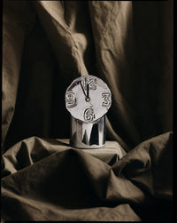 Decorative clock with Roman numerals on a draped fabric background
