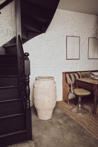 Narrow staircase leading to an upper level with a textured white wall and wooden furniture.