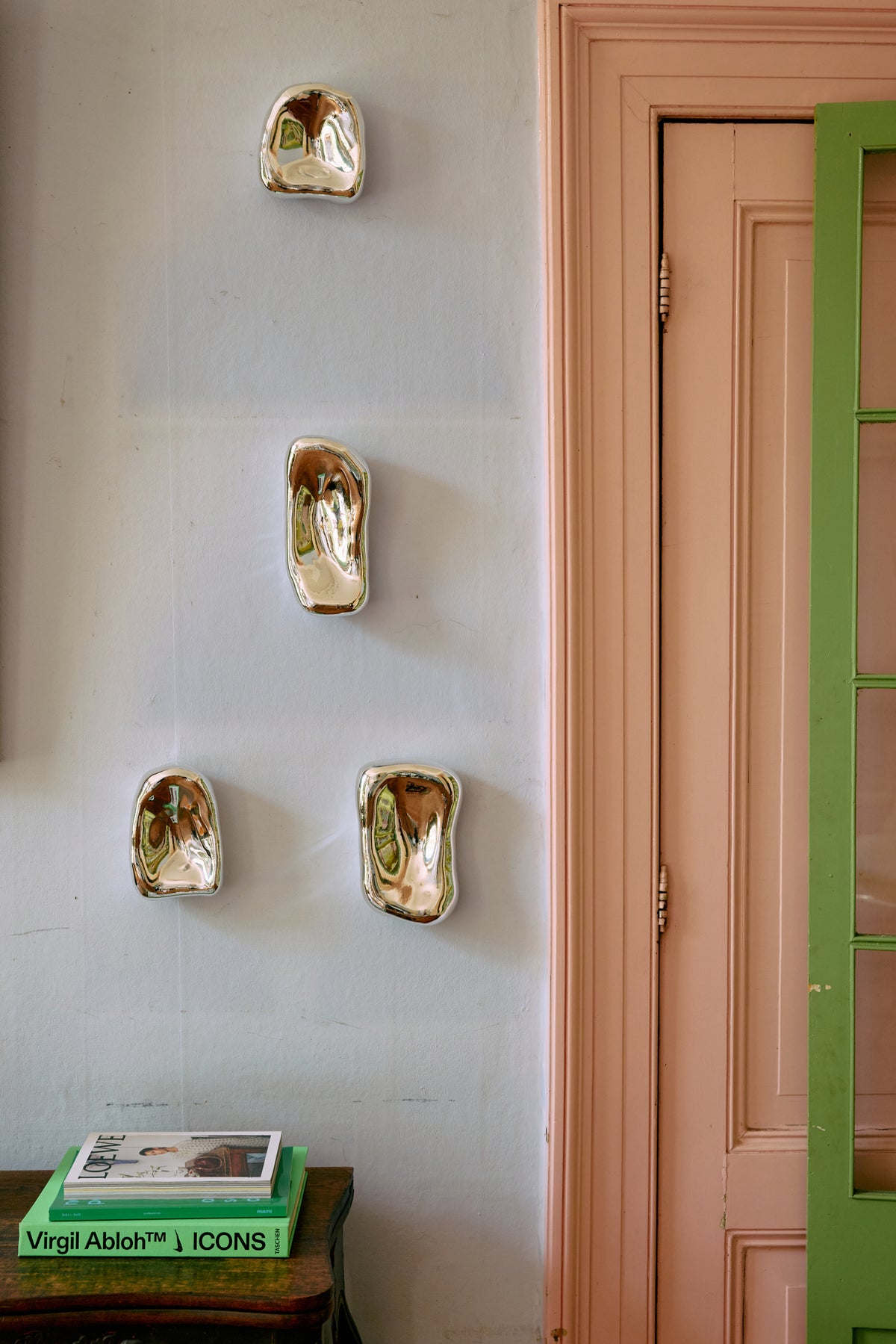 Decorative wall art on a light gray wall with a door and green frame in the background.