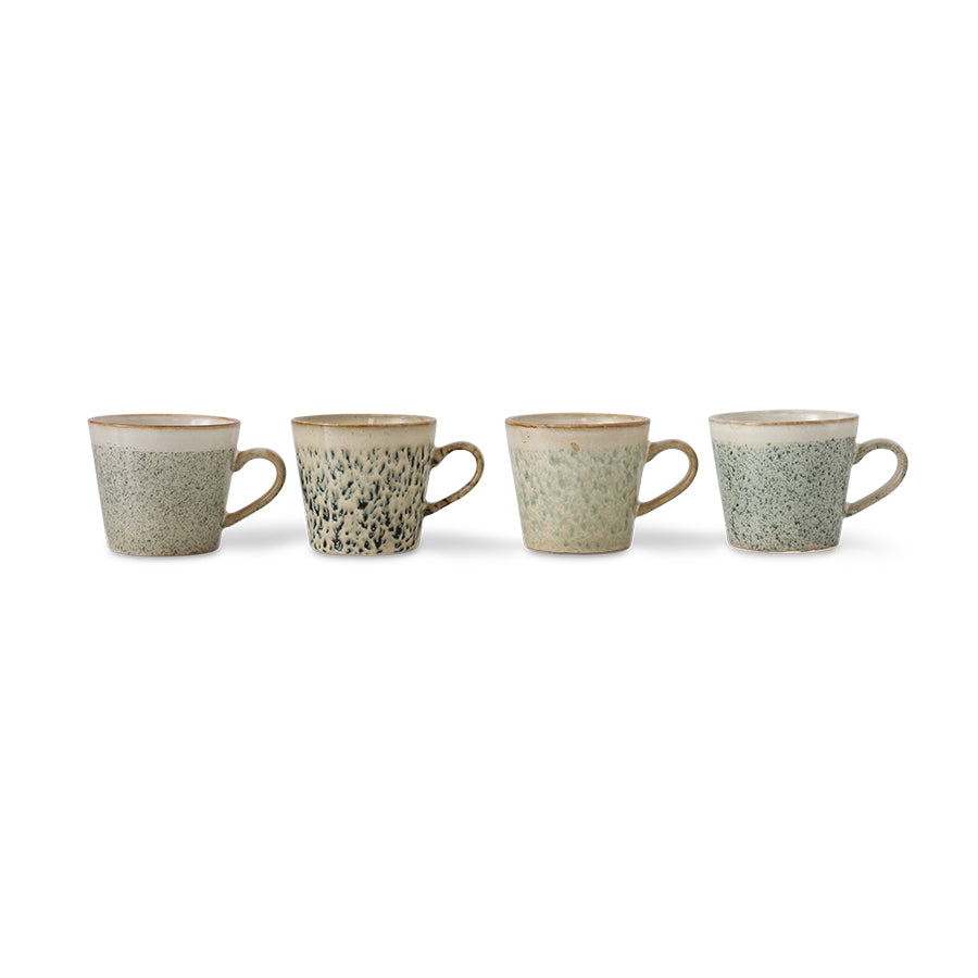four ceramic mugs with speckled pattern on a white background
