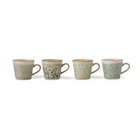 four ceramic mugs with speckled pattern on a white background
