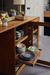Wooden kitchen island with open cabinet displaying ceramic plates and bowls.