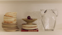 Shelving unit with books, decorative items, and a clear vase.