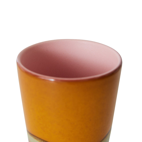 Cylindrical ceramic tumbler with a gradient color from pink to orange on a white background
