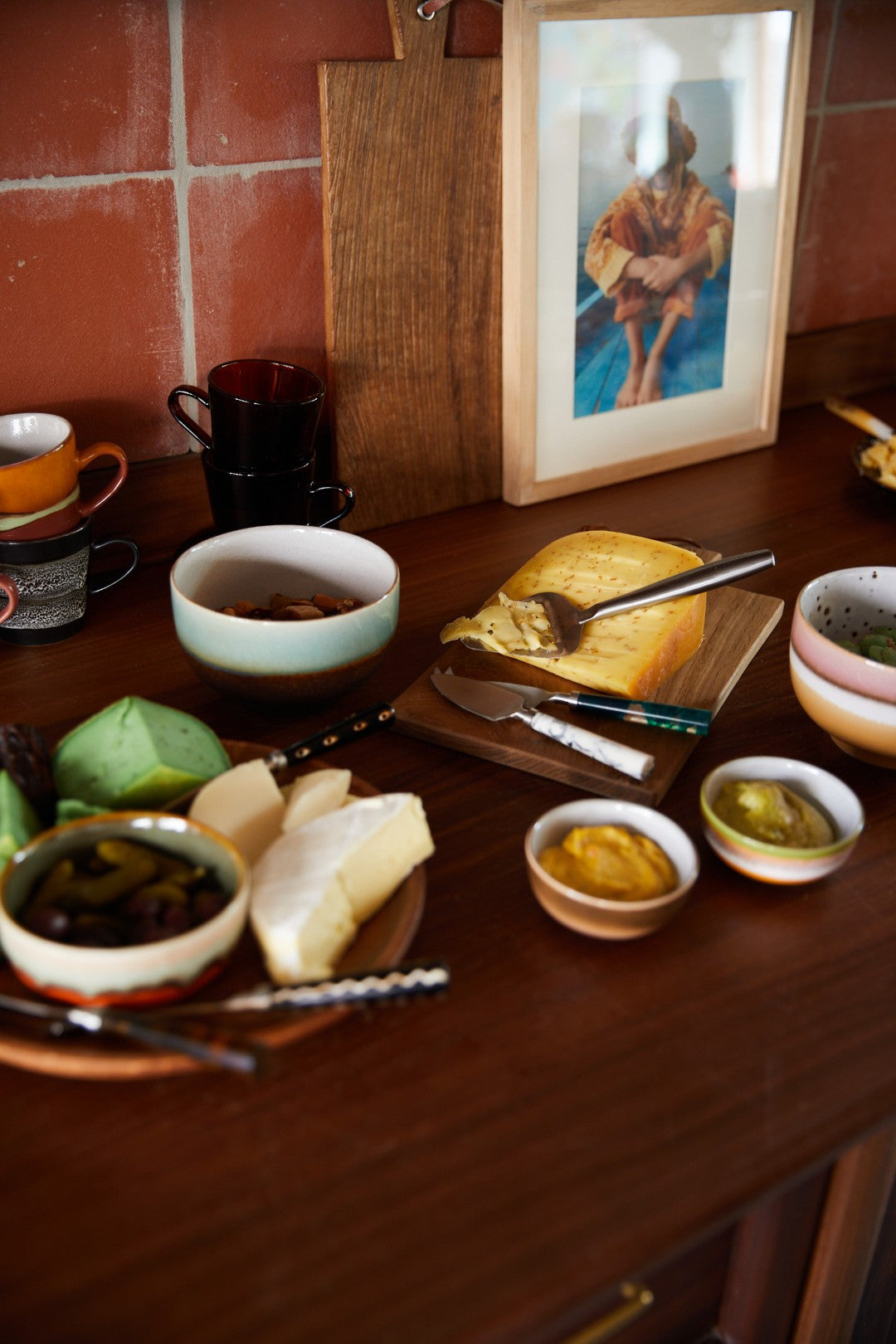 Dining table with food items and a framed picture on a tiled wall.