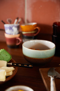 Ceramic bowls and cups on a wooden table with a blurred background