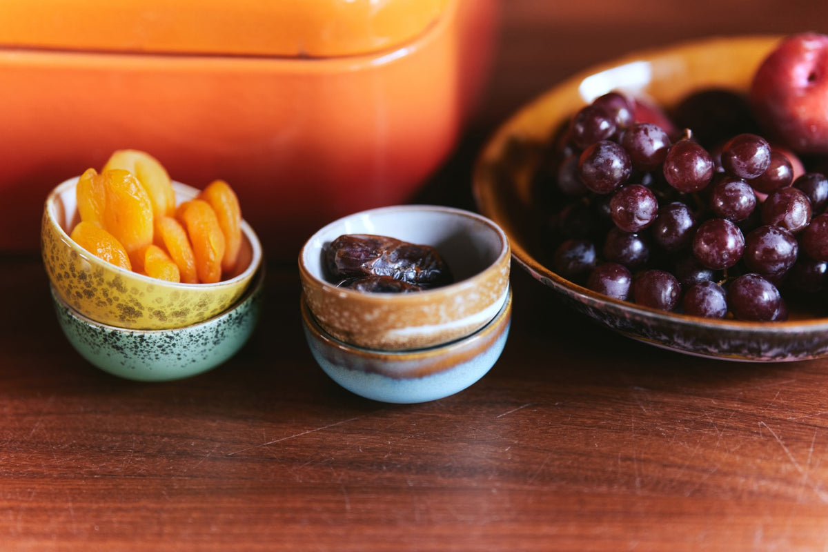 Dried fruits in small bowls on a wooden surface with a blurred background