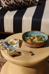 Bowl of food on a yellow table with a striped cushion in the background