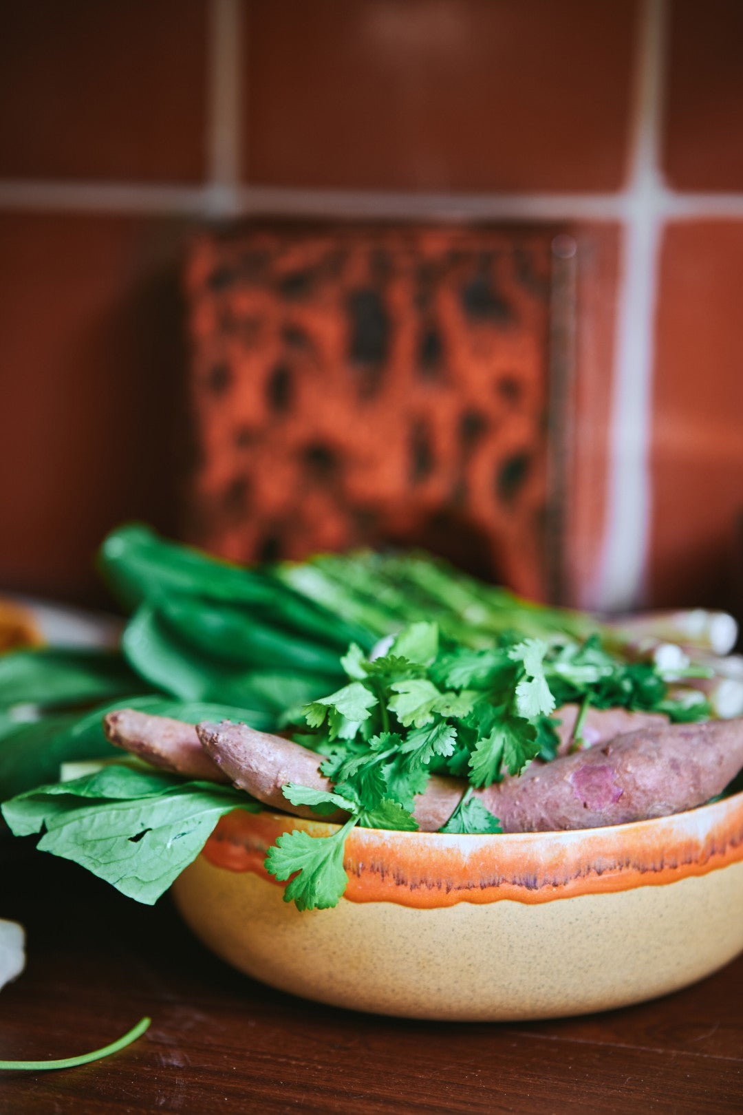 Bowl of salad with greens and meat on a wooden table.