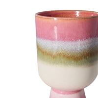 Ceramic cup with gradient pink to green color on a white background