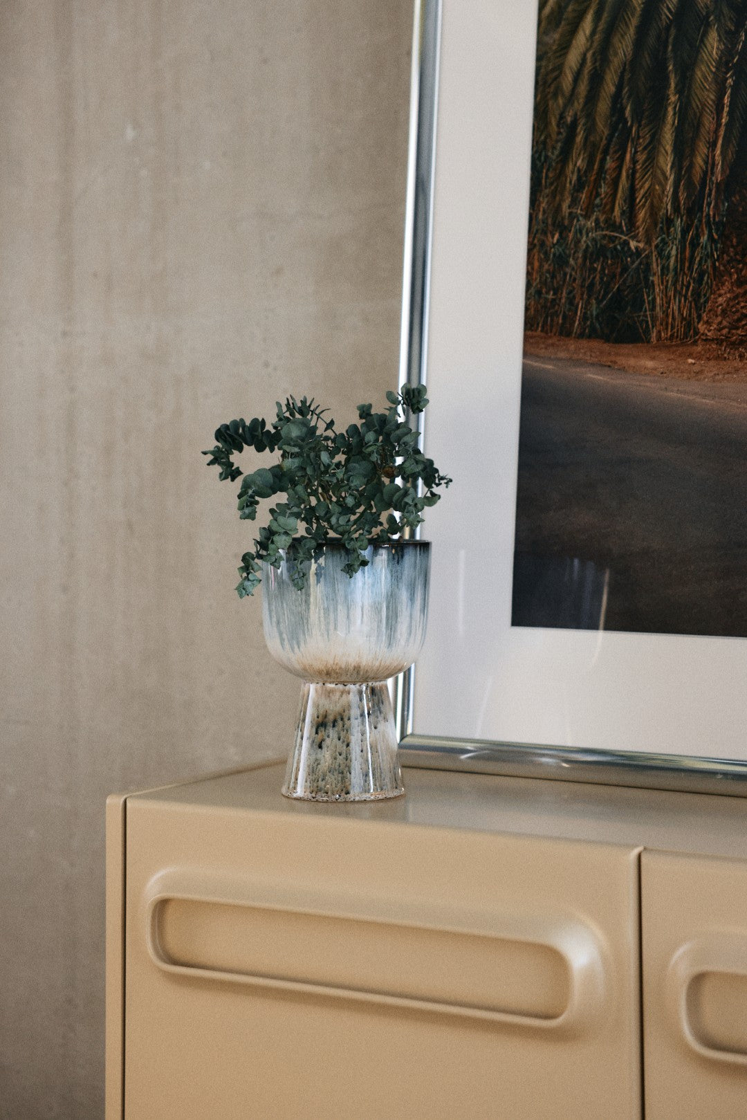 ceramic flower pot with plant in blue and brown tones on a side board