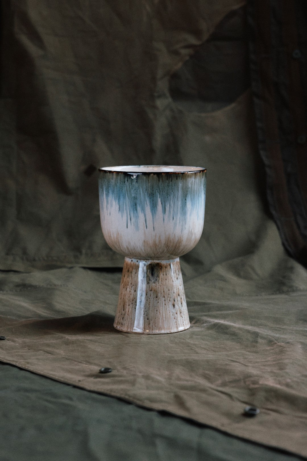 ceramic flower pot in blue and brown tones on a  taupe cloth