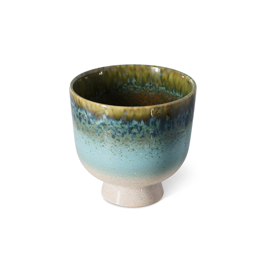Ceramic cup with green and blue glaze on a white background