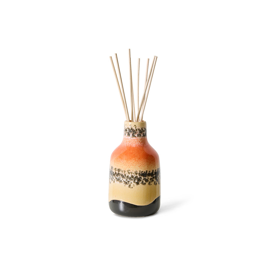 Ceramic diffuser bottle with colorful design and wooden sticks on a white background