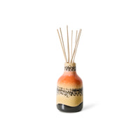 Ceramic diffuser bottle with colorful design and wooden sticks on a white background