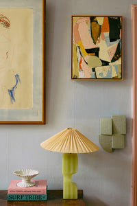 Artistic wall decor with abstract paintings and a lamp in a room setting.